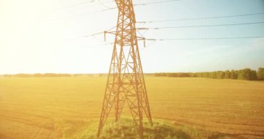 Yüksek voltajlı elektrik kulesi ve yeşil ve sarı alandaki elektrik hatları yakınında dikey hareket.