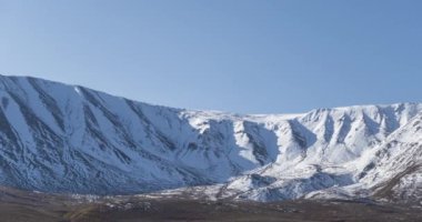 Güneşin kar dağının tepesinde kristal berrak gökyüzünde hareketinin zamanı. Sonbahar otlağında sarı çimenler. Vahşi sonsuz doğa..
