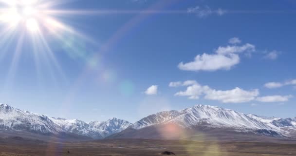 Timelapse av solens rörelse på kristallklar himmel med moln över snö bergstopp. Gult gräs på höst hög höjd äng. Vild oändlig natur. — Stockvideo