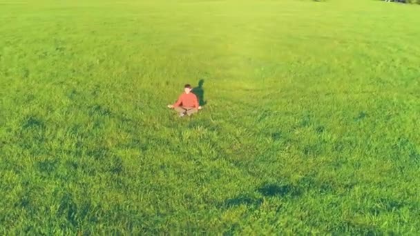 Low altitude radial flight over sport yoga man at perfect green grass. Sunset in mountain. — Stock Video