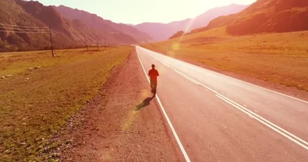 Voo de baixa altitude na frente do homem desportivo na estrada de asfalto perfeito — Vídeo de Stock