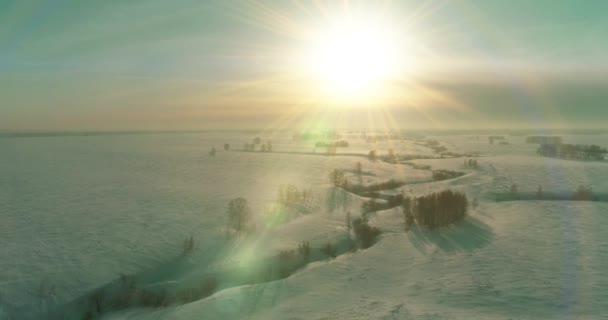 Luftaufnahme der kalten Winterlandschaft arktisches Feld, Bäume mit Frost Schnee, Eis Fluss und Sonnenstrahlen über Horizont bedeckt. Extrem niedrige Temperaturen. — Stockvideo