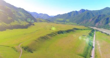 Güneşli yaz sabahında havadan kırsal dağ yolu ve çayır. Asfalt karayolu ve nehir.