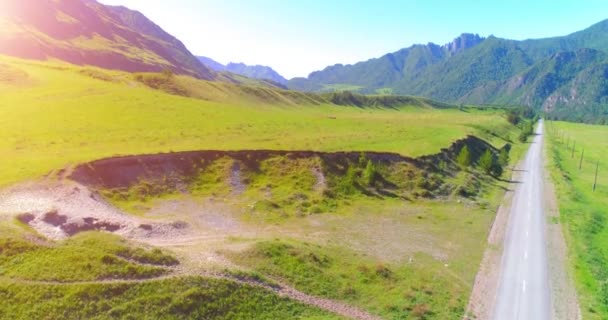 Luchtfoto landelijke bergweg en weide op zonnige zomerochtend. Asfaltweg en rivier. — Stockvideo