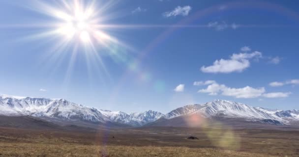 Timelapse do movimento do sol no céu cristalino com nuvens sobre o topo da montanha de neve. Grama amarela no outono prado de alta altitude. Natureza infinita selvagem. — Vídeo de Stock