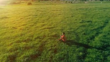 Yeşil çimlerde spor yogacısı üzerinde alçak irtifa radyal uçuş. Dağda gün batımı.
