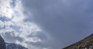 Yaz ya da sonbahar zamanı dağ vadisindeki destansı bulutların zamanı. Vahşi sonsuz doğa ve kar fırtınası gökyüzü. Kar zirvesinde güneş ışınları