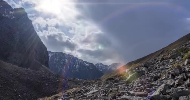 Timelapse of epic clouds in mountain valley at summer or autumn time. Wild endless nature and snow storm sky. Sun rays over snow summit — Stock Video