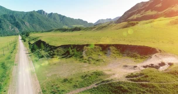 Luftlinie ländliche Bergstraße und Wiese an einem sonnigen Sommermorgen. Asphaltstraße und Fluss. — Stockvideo