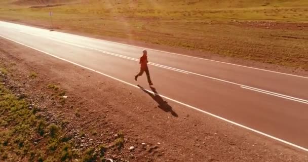 Vuelo de baja altitud frente al deportista en el camino perfecto de asfalto — Vídeo de stock