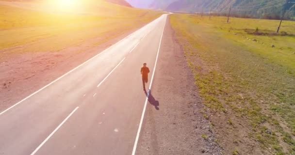 Voo de baixa altitude na frente do homem desportivo na estrada de asfalto perfeito — Vídeo de Stock