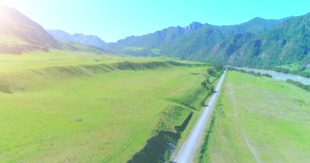 Luftlinie ländliche Bergstraße und Wiese an einem sonnigen Sommermorgen. Asphaltstraße und Fluss. — Stockvideo