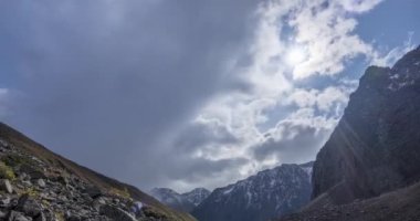 Yaz ya da sonbahar zamanı dağ vadisindeki destansı bulutların zamanı. Vahşi sonsuz doğa ve kar fırtınası gökyüzü. Kar zirvesinde güneş ışınları