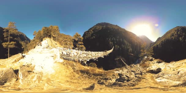 Largest suspension bridge in Khumbu valley with colorful Tibetan prayer flags. Wild Himalayas high altitude nature and mount valley. Rocky slopes covered with trees. Base camp of Everest peak trek. — Stock Video