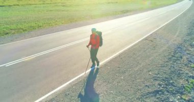 Asfalt yolda yürüyen otostopçu turist üzerinden uçuş. Yaz günü büyük bir kırsal vadi. Sırt çantalı gezgin..