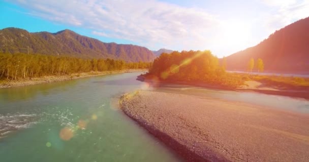 4k UHD aerial view. Low flight over fresh cold mountain river at sunny summer morning. Green trees and sun rays on horisont — Stock Video