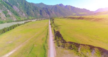 Güneşli yaz sabahında havadan kırsal dağ yolu ve çayır. Asfalt karayolu ve nehir.