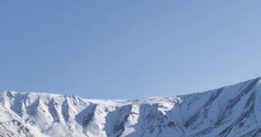 Güneşin kar dağının tepesinde kristal berrak gökyüzünde hareketinin zamanı. Sonbahar otlağında sarı çimenler. Vahşi sonsuz doğa..
