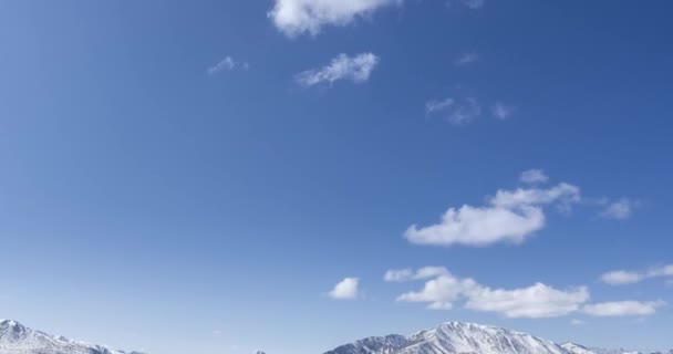 Timelapse du mouvement du soleil sur un ciel cristallin avec des nuages sur le sommet de la montagne de neige. Herbe jaune à l'automne prairie de haute altitude. Nature sauvage sans fin. — Video