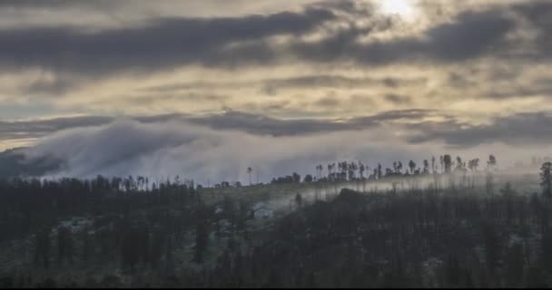 Timelapse of evening sun rays emerging through the cold foggy clouds in the mountains. Sunset in mountain fog. — Stock Video