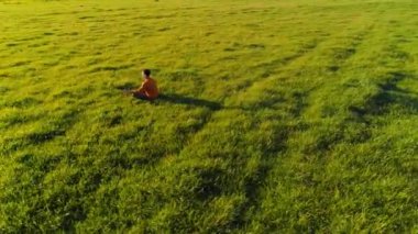 Yeşil çimlerde spor yogacısı üzerinde alçak irtifa radyal uçuş. Dağda gün batımı.