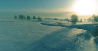 Soğuk kış manzarası kutup bölgesi, karla kaplı ağaçlar, ufukta buz nehri ve güneş ışınları. Aşırı düşük sıcaklık havası.