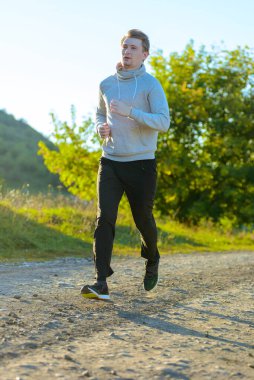 Güzel bir yaz gününde kırsal kesimde koşan bir adam. Spor fitness modeli Kafkasya etnik köken eğitimi.