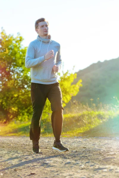 Чоловік біжить у сільській місцевості в прекрасний літній день. Спортивна фітнес-модель кавказької етнічної підготовки на відкритому повітрі . — стокове фото