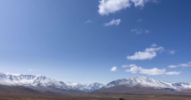 Timelapse du mouvement du soleil sur un ciel cristallin avec des nuages sur le sommet de la montagne de neige. Herbe jaune à l'automne prairie de haute altitude. Nature sauvage sans fin. — Video