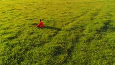 Yeşil çimlerde spor yogacısı üzerinde alçak irtifa radyal uçuş. Dağda gün batımı.