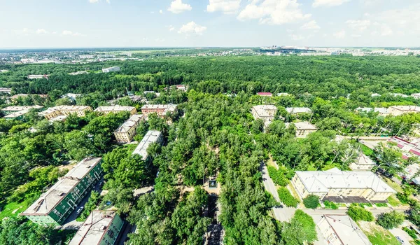 Vista aérea de la ciudad con encrucijadas y caminos, casas, edificios, parques y estacionamientos. Imagen panorámica soleada de verano — Foto de Stock