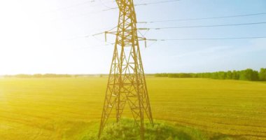 Yüksek voltajlı elektrik kulesi ve yeşil ve sarı alandaki elektrik hatları yakınında dikey hareket.