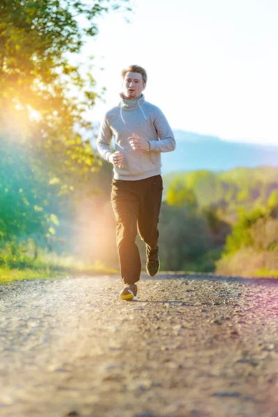 Man jogging in rural nature at beautiful summer day. Sport fitness model caucasian ethnicity training outdoor.