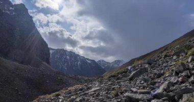 Yaz ya da sonbahar zamanı dağ vadisindeki destansı bulutların zamanı. Vahşi sonsuz doğa ve kar fırtınası gökyüzü. Kar zirvesinde güneş ışınları