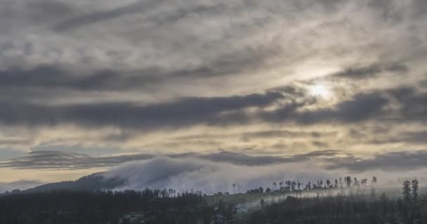 Timelapse des rayons du soleil du soir émergeant à travers les nuages brumeux froids dans les montagnes. Coucher de soleil dans le brouillard montagneux. — Video