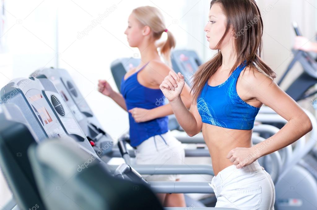 Women run on machine in gym