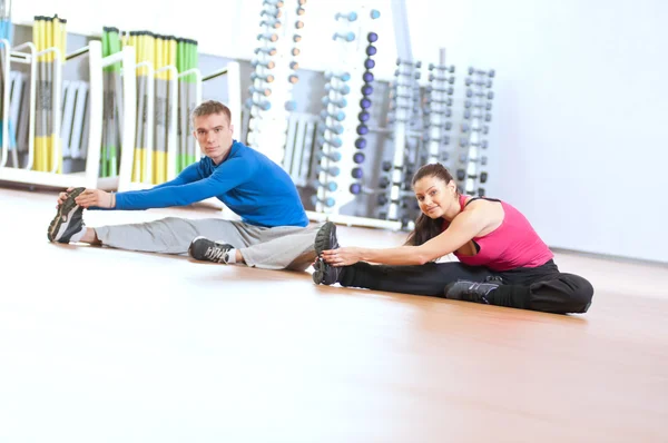 Мужчина и женщина делают растяжку в спортзале — стоковое фото