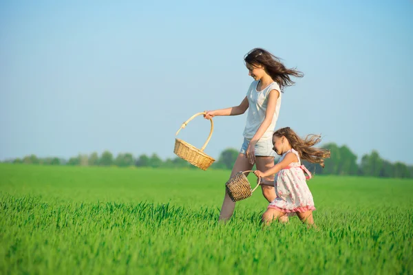 Girls running with baskets at green field — Stock Photo, Image