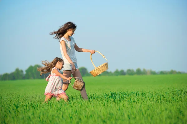 Chicas corriendo con canastas en el campo verde —  Fotos de Stock