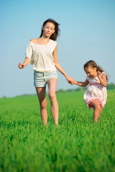 Meisjes lopen bij groene tarweveld — Stockfoto