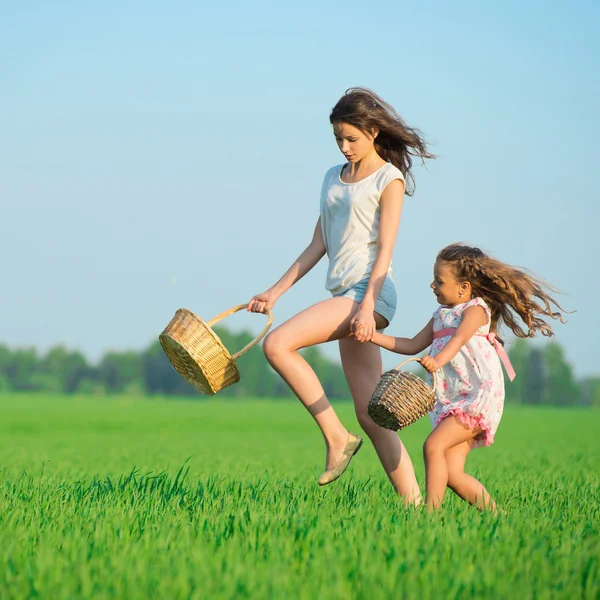 Ragazze in esecuzione con cestini a campo verde — Foto Stock