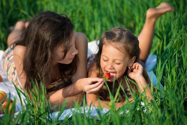 Gelukkig meisjes op groen gras met aardbeien — Stockfoto