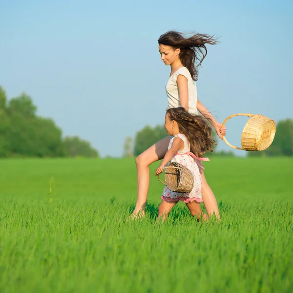 Chicas corriendo con canastas en el campo verde —  Fotos de Stock