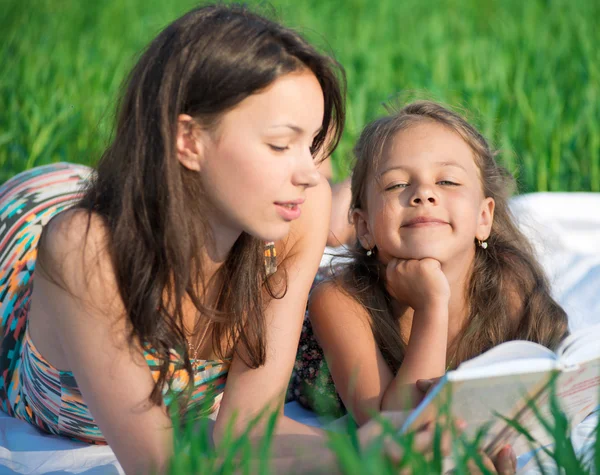 Girls reading book on green grass — Stock Photo, Image