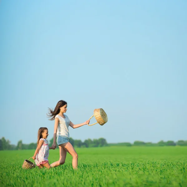 Ragazze in esecuzione con cestini a campo verde — Foto Stock