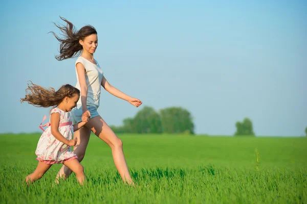 Κορίτσια τρέχουν στο πεδίο πράσινο σιτάρι — Φωτογραφία Αρχείου