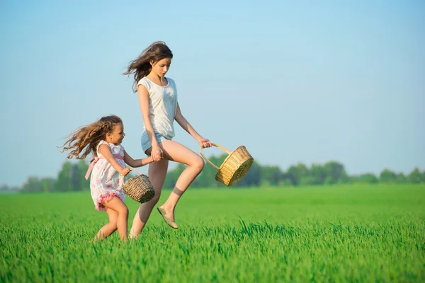 Girls running with baskets at green field — Stock Photo, Image