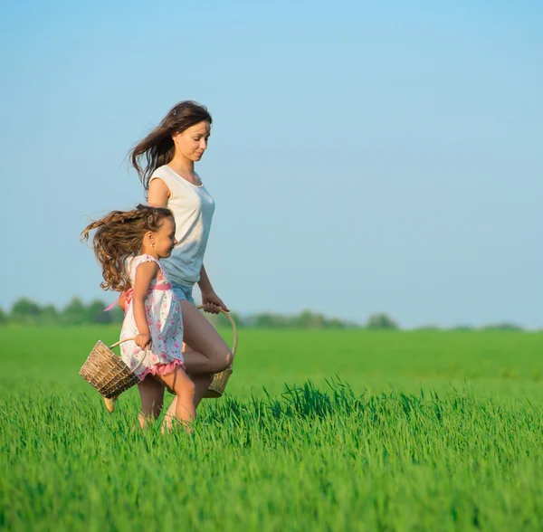 Chicas corriendo con canastas en el campo verde —  Fotos de Stock