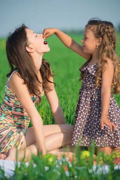 Girls eating cherry fruit at picnic — Stock Photo, Image