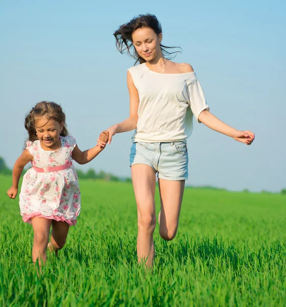 Meisjes lopen bij groene tarweveld — Stockfoto